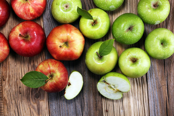 Ripe red apples with leaves on wooden background.