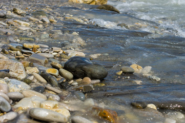 pebble stones on the sea beach, the rolling waves of the sea with foam