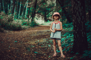 Portrait of a posing caucasian little girl on the background of the forest. Pastel summer colors,...