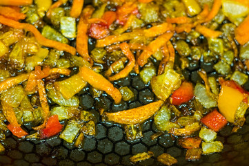 cooking a roast for soup of onions, carrots, paprika, tomatoes, herbs and spices in sunflower oil in a frying pan