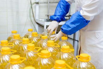 line of production of refined sunflower oil. Girl worker at a factory on a conveyor background with bottles of vegetable oil.