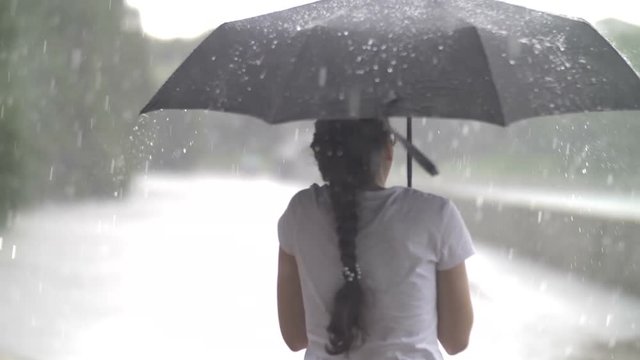 happy girl under the umbrella enjoying in the rain, heavy rain, slow motion