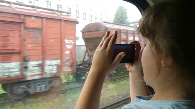 A teenager with a gadget in a long-distance train car. A teenager photographs a smartphone in a train car.