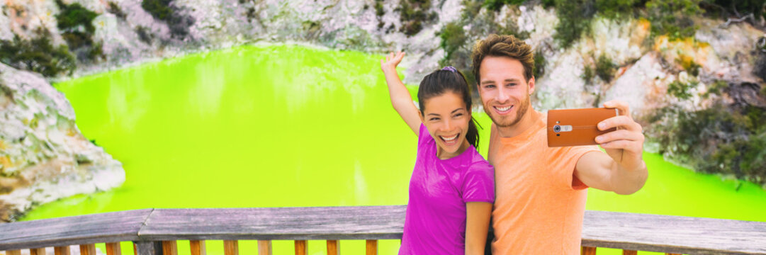 New Zealand tourism travel destination people lifestyle. Banner panorama. Couple tourists taking selfie travel destination, Waiotapu. Active geothermal green pond, Rotorua, north island, Wai-O-Tapu.