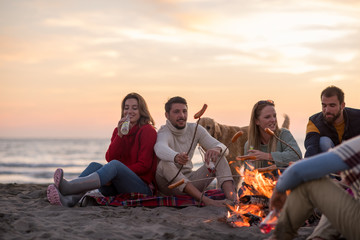 Group Of Young Friends Sitting By The Fire at beach