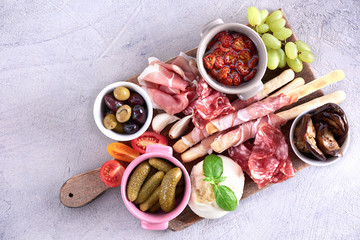 Italian antipasti wine snacks set. Grizini, cheese variety, Mediterranean olives, pickles, Prosciutto, salami white background, top view