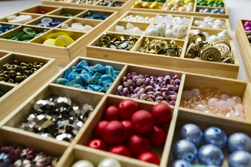 Clothes buttons in wooden boxes on white cardboard background. Closeup photo.