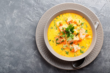 Salmon soup with cream, potatoes, carrots and parsley on gray background. top view.