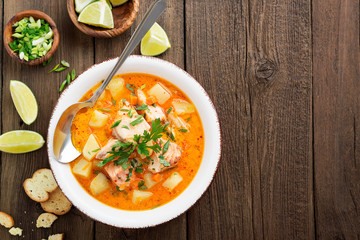 Salmon soup with cream, potatoes, carrots and parsley on gray background. top view.