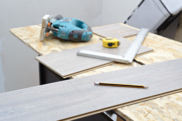 DIY, repair, building and home concept - close up of male hands lying parquet floor board/laminate flooring