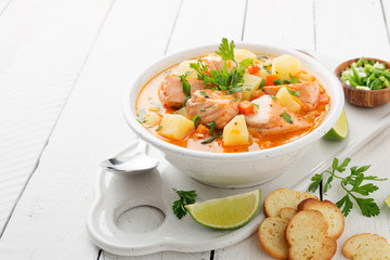 Salmon soup with cream, potatoes, carrots and parsley on white background.