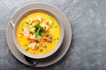 Salmon soup with cream, potatoes, carrots and parsley on gray background. top view.