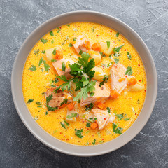 Salmon soup with cream, potatoes, carrots and parsley on gray background. top view.