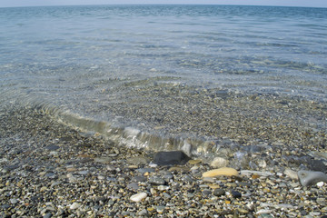 Clear and quiet sea water with stones and little wave. Sea beach.