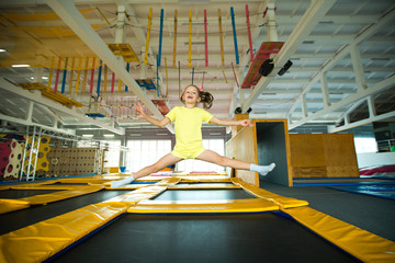 beautiful little girl jumping on a trampoline in a game club