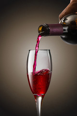 Pouring red wine into the glass against on black background