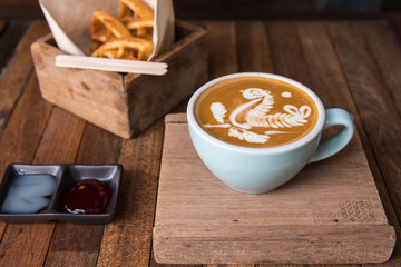 Latte art coffee cup  with snack on wooden table