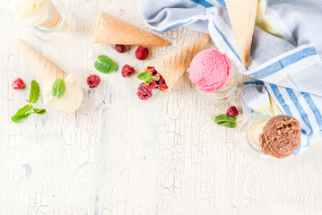 Fototapeta na wymiar Summer sweet berries and desserts, various of ice cream flavor in cones pink (raspberry), vanilla and chocolate with mint on light concrete background copy space top view