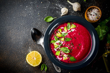 Vegan food, summer cold Beetroot gazpacho soup with lemon, avocado and fresh herbs copy space top view