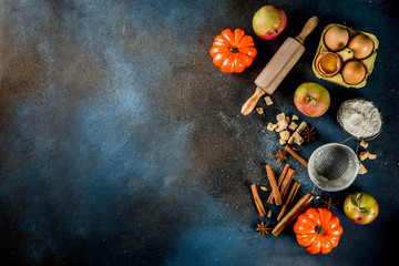 Sweet autumn baking concept, cooking background with baking accessories, flour, rolling pin, decorative pumpkins, apples, cinnamon spices with anise cardamom sugar. 