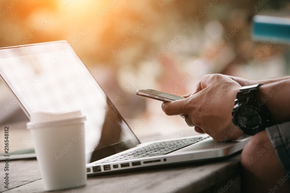 Wall mural man using internet on smart phone and laptop