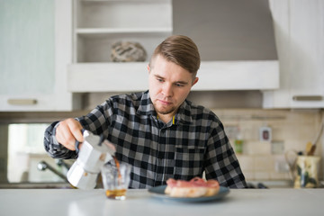 Morning, drink and people concept - Portrait of handsome man pouring coffee in a coffee mug at the kitchen