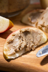 homemade peanut butter on a piece of apple, vertical