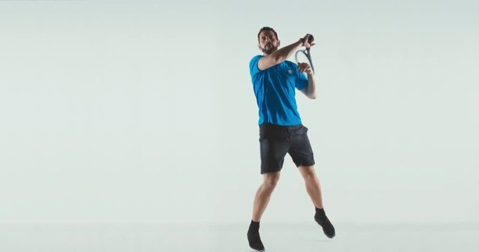 Caucasian male tennis player posing as if he was hitting a ball against white background. 4K UHD 60 FPS SLOW MOTION