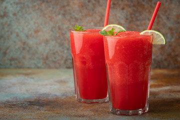 Watermelon slushie with lime, summer refreshing drink in tall glasses on a blue rusty background. with copy space