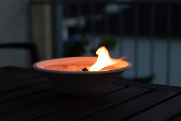 Burning candle on a wooden table in the garden 