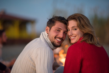 Fototapeta premium Couple enjoying with friends at sunset on the beach
