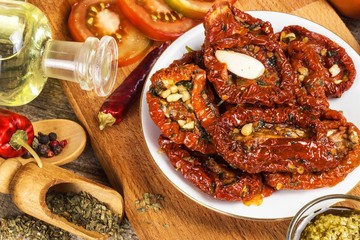 Dried tomatoes pickled in olive oil with garlic. Sunflower seeds with tomatoes on an old wooden table.