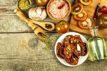 Dried tomatoes pickled in olive oil with garlic. Sunflower seeds with tomatoes on an old wooden table.