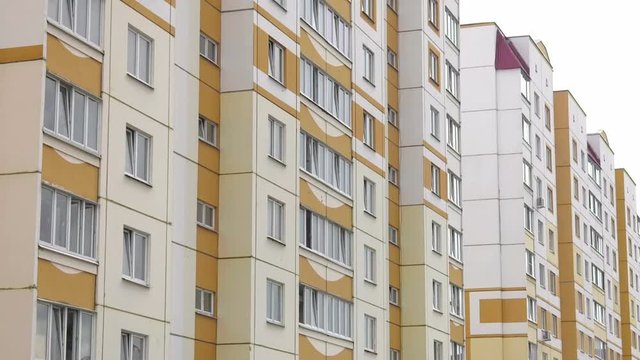 New multi-apartment panel house with glazed loggias and balconies. Frame-panel buildings. The panels are painted white and olive-colored.