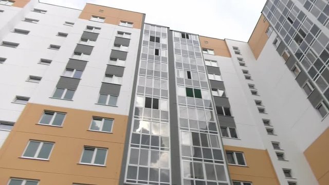 New multi-apartment panel house with glazed loggias and balconies. Frame-panel buildings. The panels are painted in ocher color, gray and white.