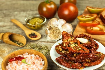 Dried tomatoes pickled in olive oil with garlic. Sunflower seeds with tomatoes on an old wooden table.