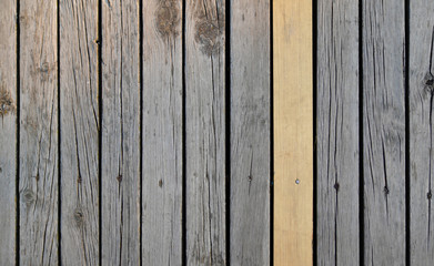 One new wooden plank among old wooden planks. Concept of replace and partial renovate