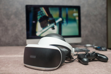helmet virtual reality and game joystick lie on the couch in the background of the monitor © silentalex88