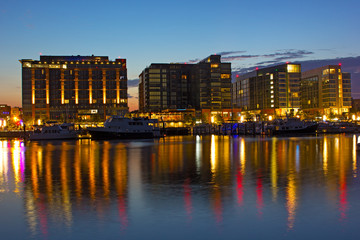 Residential buildings near waterfront and marina at dawn in Washington DC. The Wharf district buildings and their colorful reflection in Potomac River.