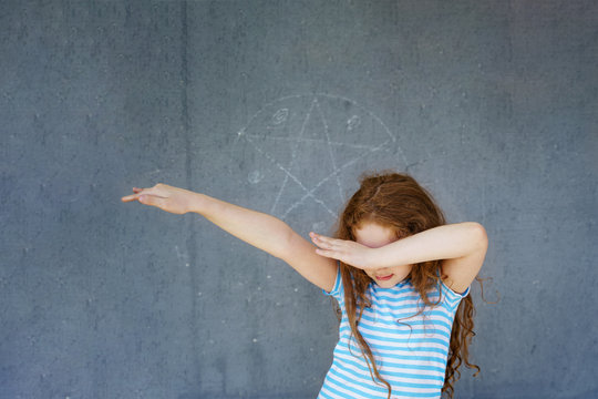 Cute Girl Dancing Dab On Grey Wall Background.