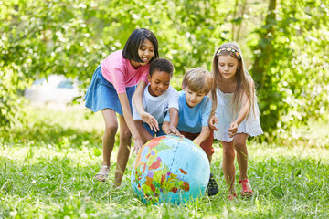 Multikulturelle Gruppe Kinder rollt Weltkugel