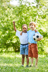 Zwei Jungen mit Fußball als Freunde jubeln