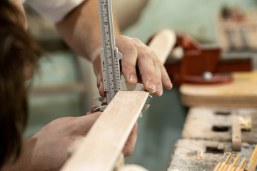 Mann kontrolliert das Maß des Holzwerkstücks in einer Werkstatt