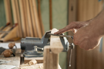 Fototapeta na wymiar Mann arbeitet mit einer Raspel auf Holzwerkstück in einer Werkstatt
