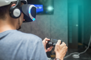 Young Man Wearing VR Headset And Experiencing Virtual Reality and plays games with the joystick at...