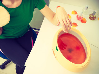 Woman getting paraffin hand treatment at beautician