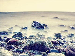  Peaceful morning sea level with stones in peaceful sea level. Pink horizon