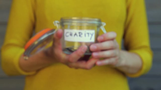 Woman collecting money for charity and holds jar with coins.