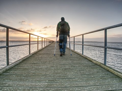 Hurt Man With Hooded Jacket And Forearm Crutches  Looking Sadly