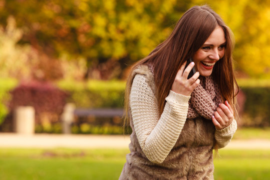 Girl talking on mobile phone in autumn park